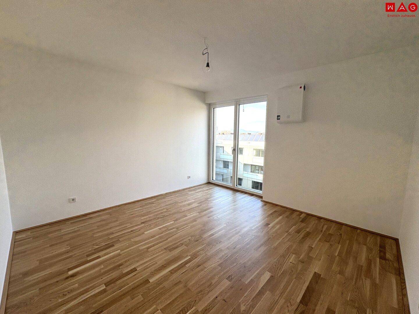 Geräumiges Schlafzimmer mit Holzboden und großen Fenstern, bereit für individuelle Gestaltung.