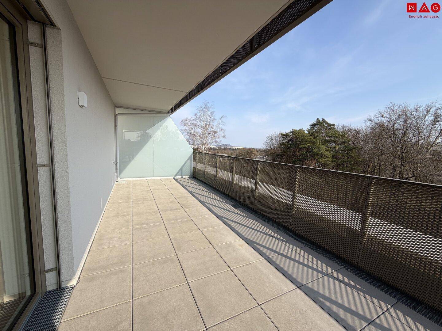 Langer, schmaler Balkon mit Fliesenboden und Blick ins Grüne, ideal für frische Luft.