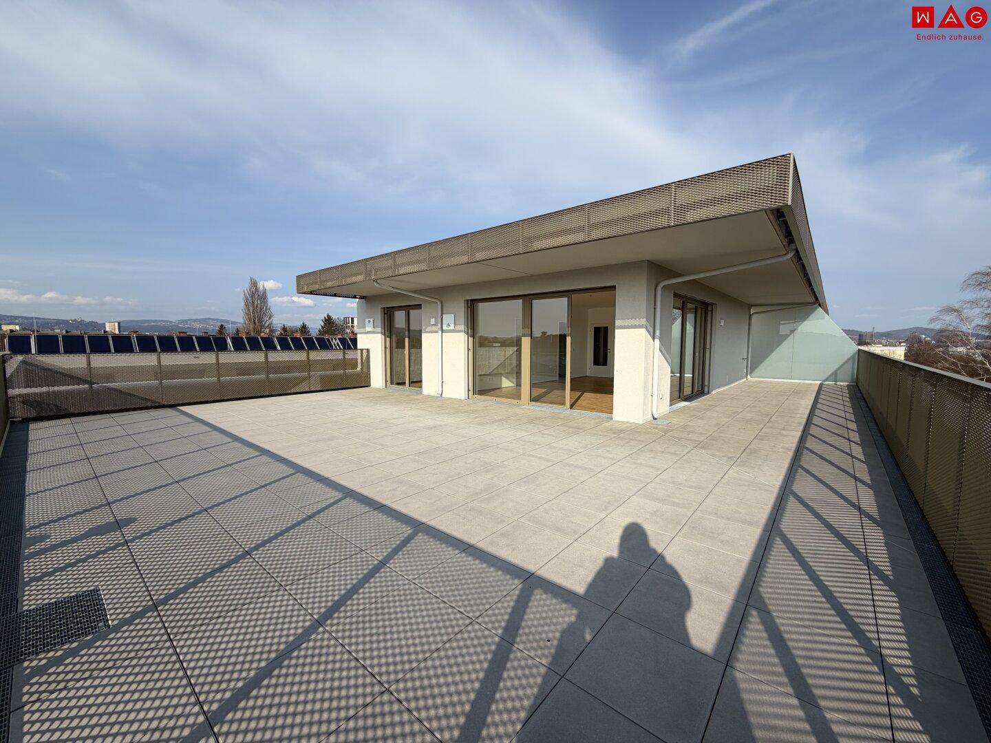 Moderne Architektur mit großer Dachterrasse und bodentiefen Fenstern, die viel Licht hereinlassen.