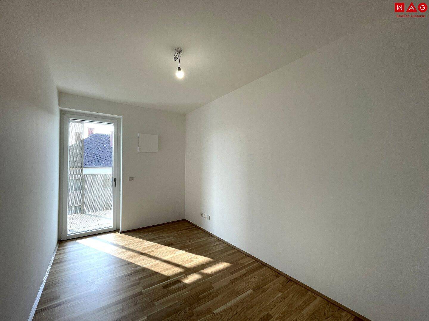 Heller, leerer Raum mit Parkettboden und großem Fenster, ideal als Büro oder Gästezimmer.
