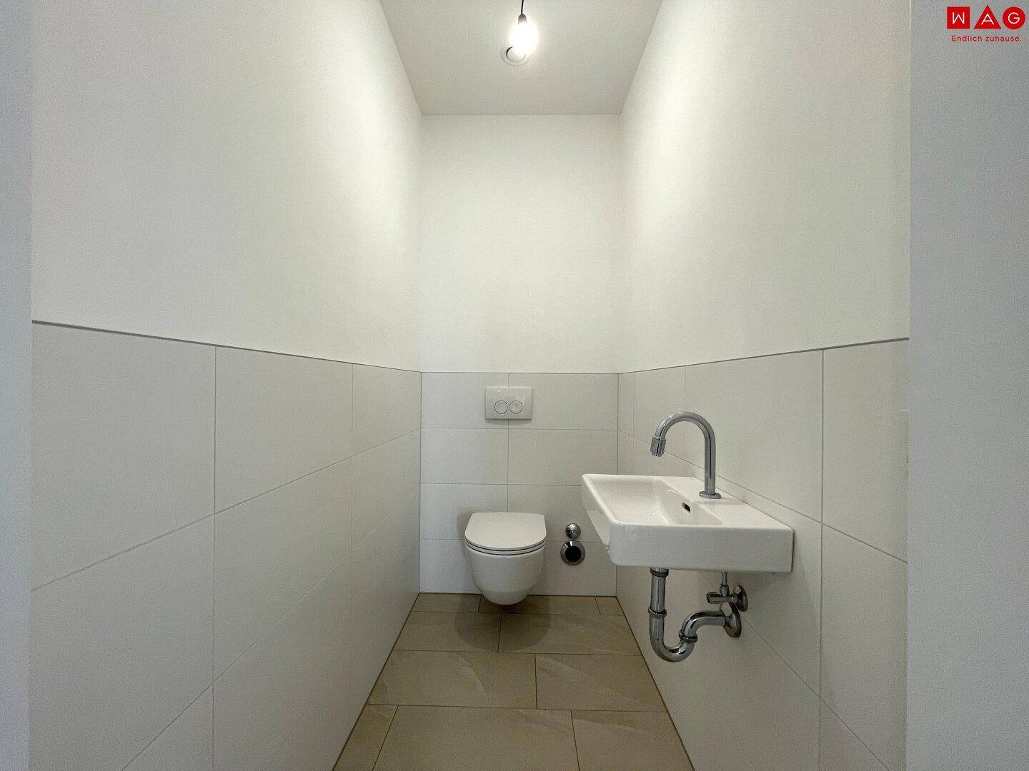 Helles Gäste-WC mit wandhängender Toilette und kleinem Waschbecken, funktional und sauber.