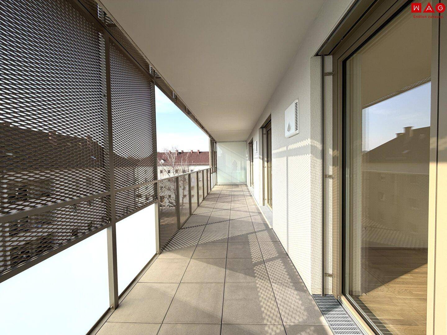 Langer Balkon mit Fliesenboden und Metallgeländer, ideal für Entspannung im Freien.