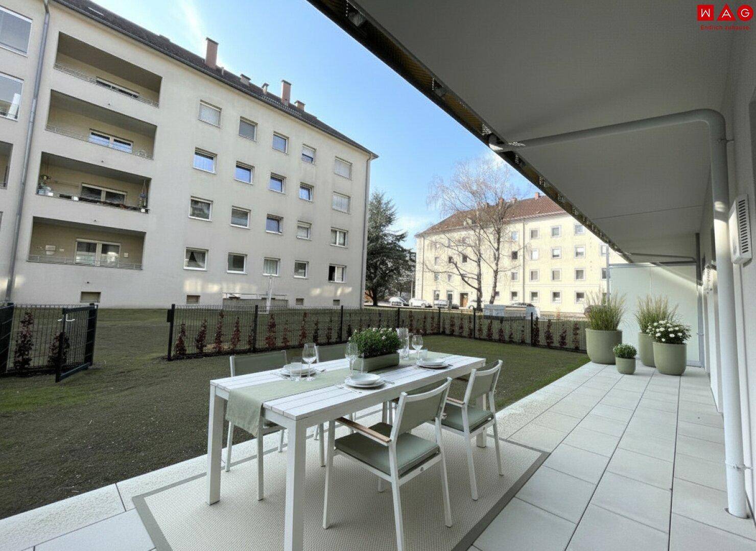 Möblierte Terrasse mit Essbereich und Pflanzen, Blick auf die Grünfläche.