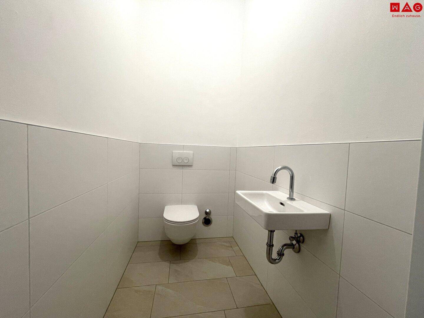 Helles Gäste-WC mit wandhängender Toilette und kleinem Waschbecken.