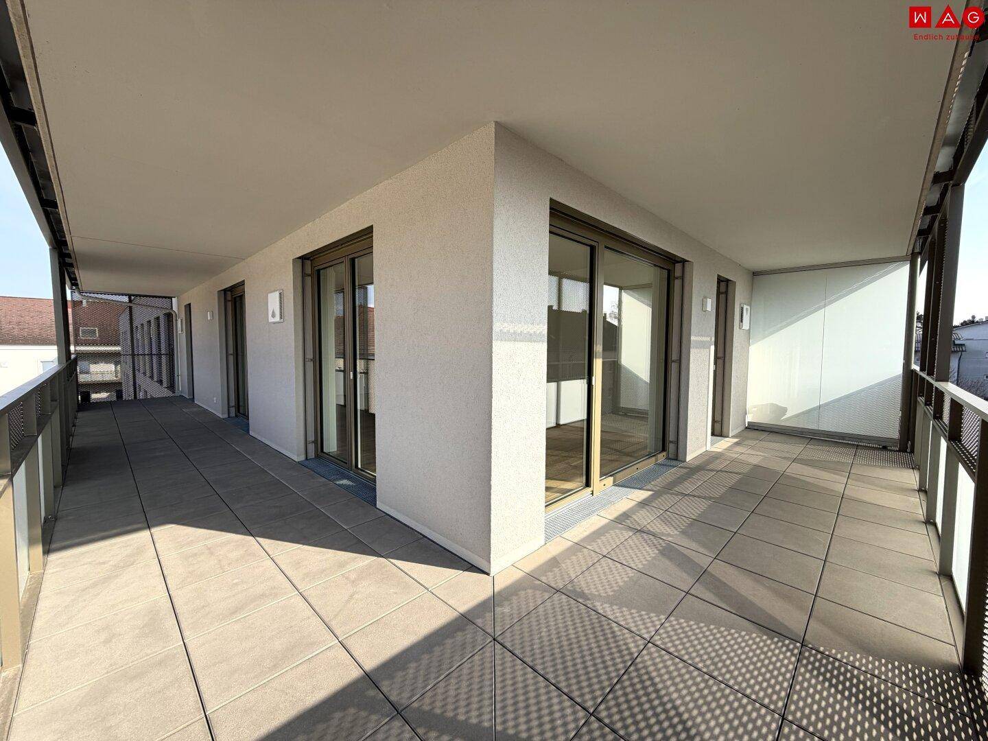 Weitläufige, leere Terrasse mit Fliesenboden und viel Tageslicht, bereit zur individuellen Gestaltung.