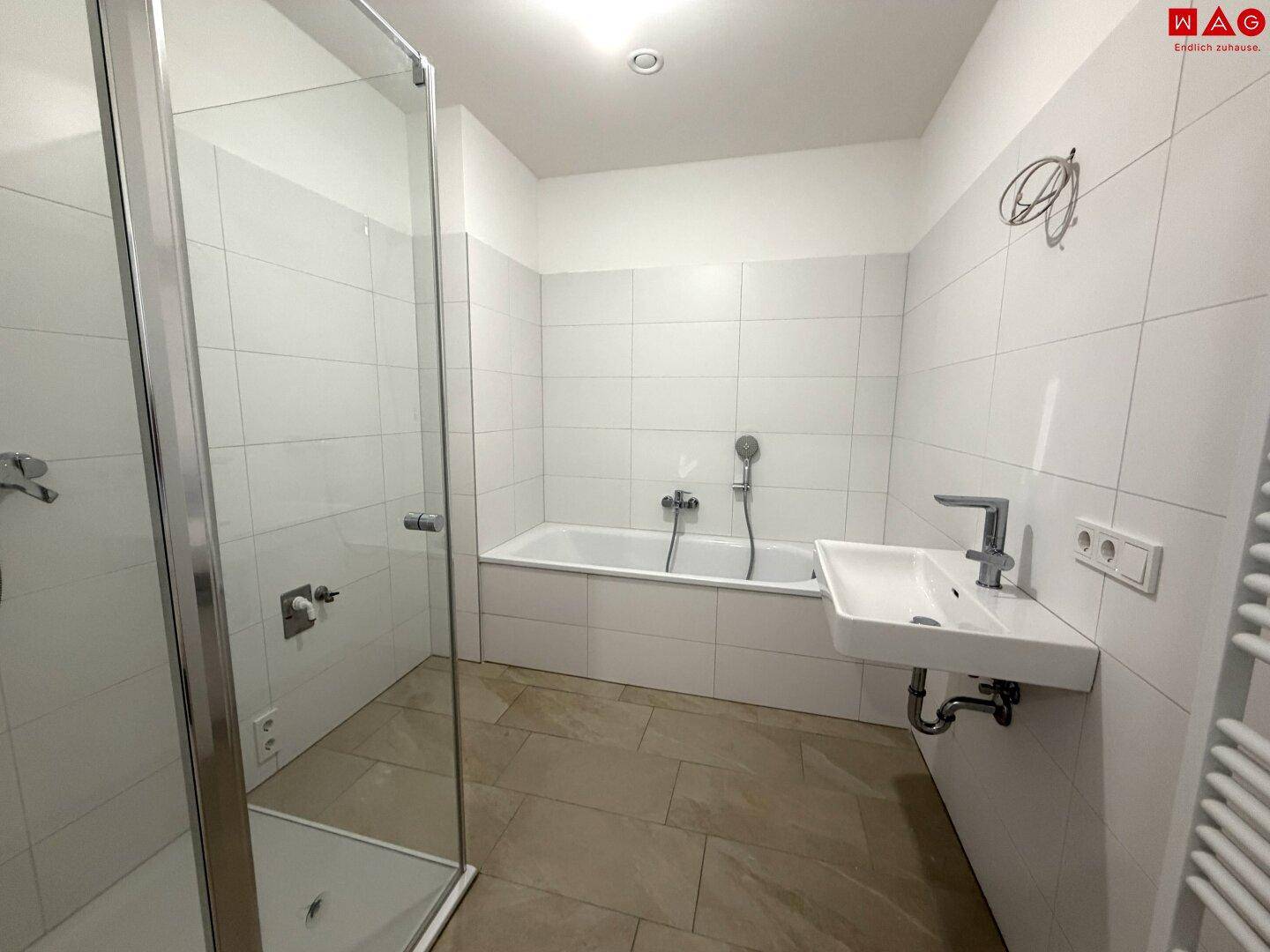 Helles Badezimmer mit Badewanne, Duschkabine und Fliesenboden, funktional gestaltet.