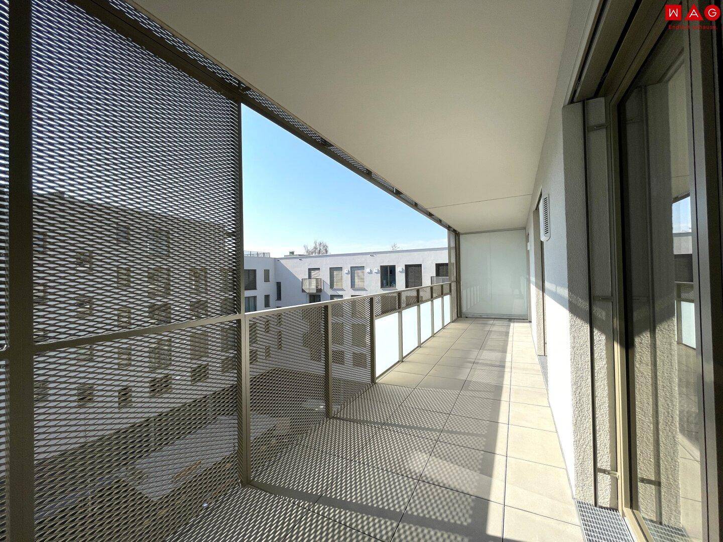 Geräumiger Balkon mit Fliesenboden und moderner Metallbrüstung, der viel Platz bietet.