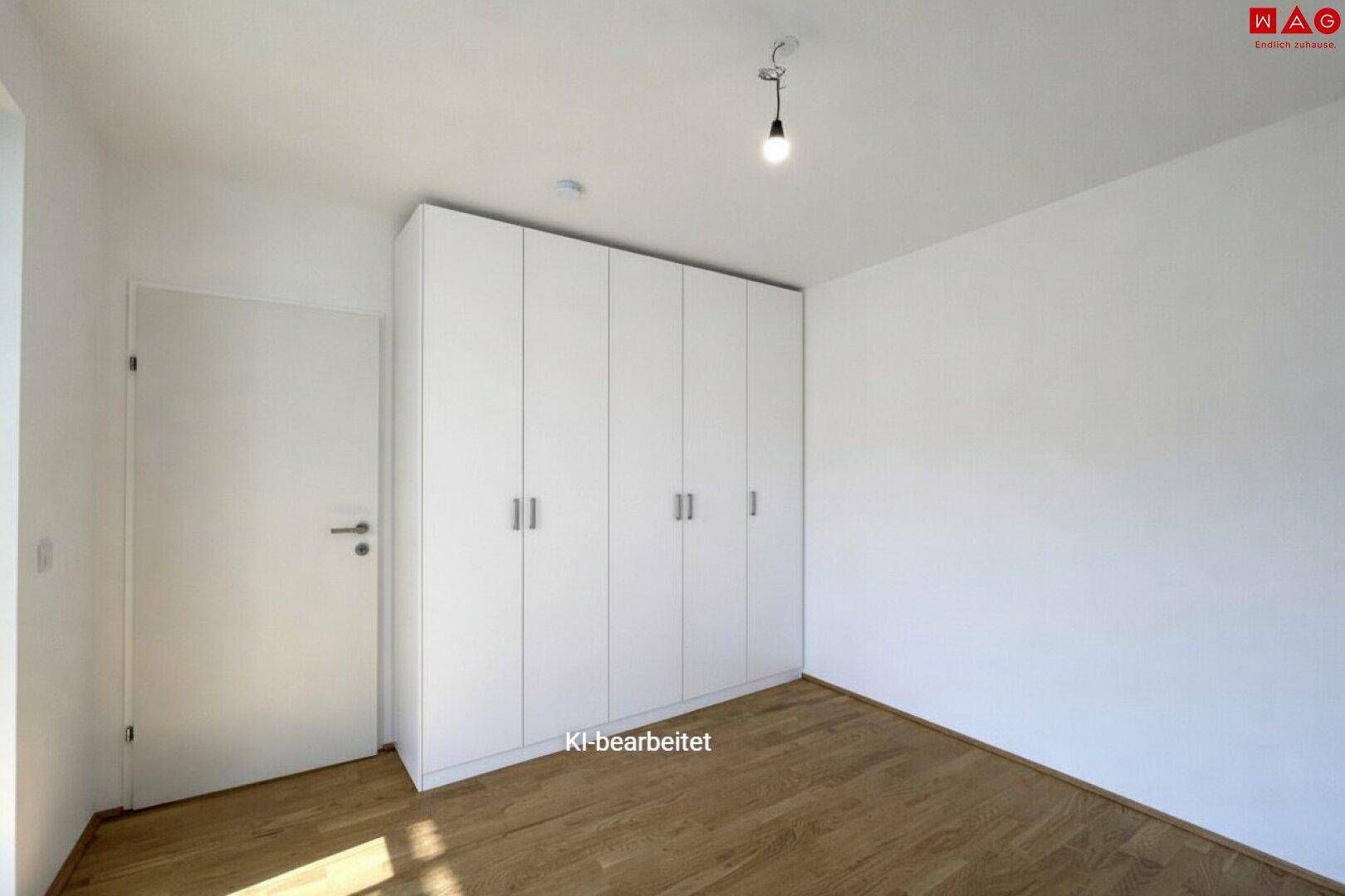 Helles Schlafzimmer mit Einbauschrank, Parkettboden und weiß gestrichenen Wänden.