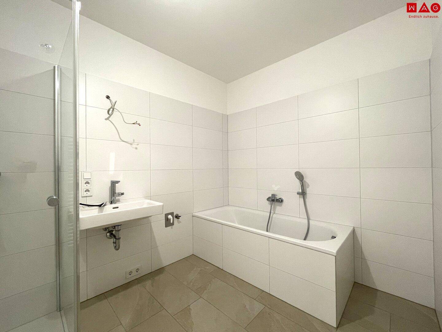 Unmöbliertes Badezimmer mit Badewanne, Duschbereich und hellen Fliesen, bereit für die Einrichtung.