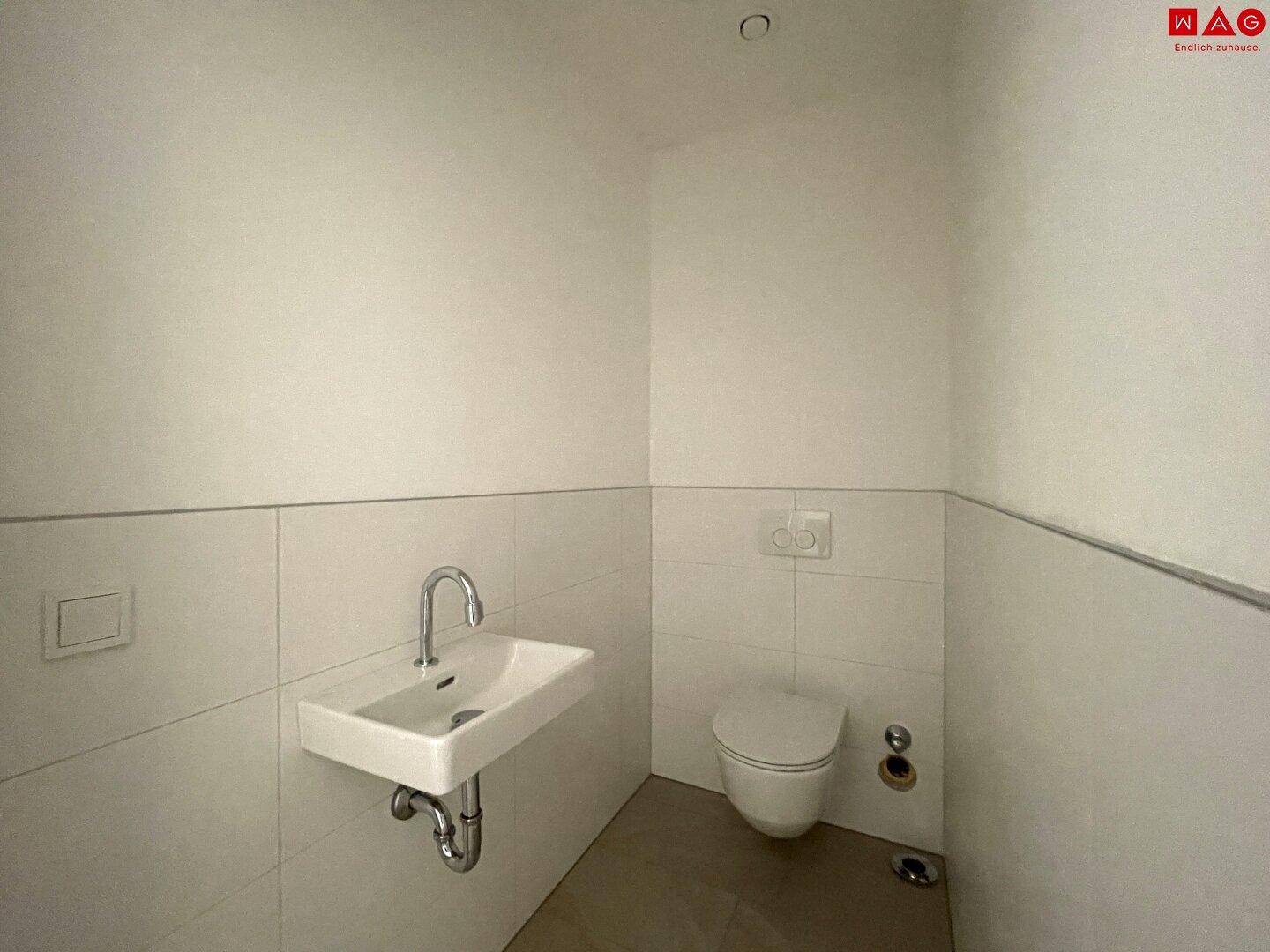 Unmöbliertes Gäste-WC mit Waschbecken und Toilette, bereit für die individuelle Gestaltung.