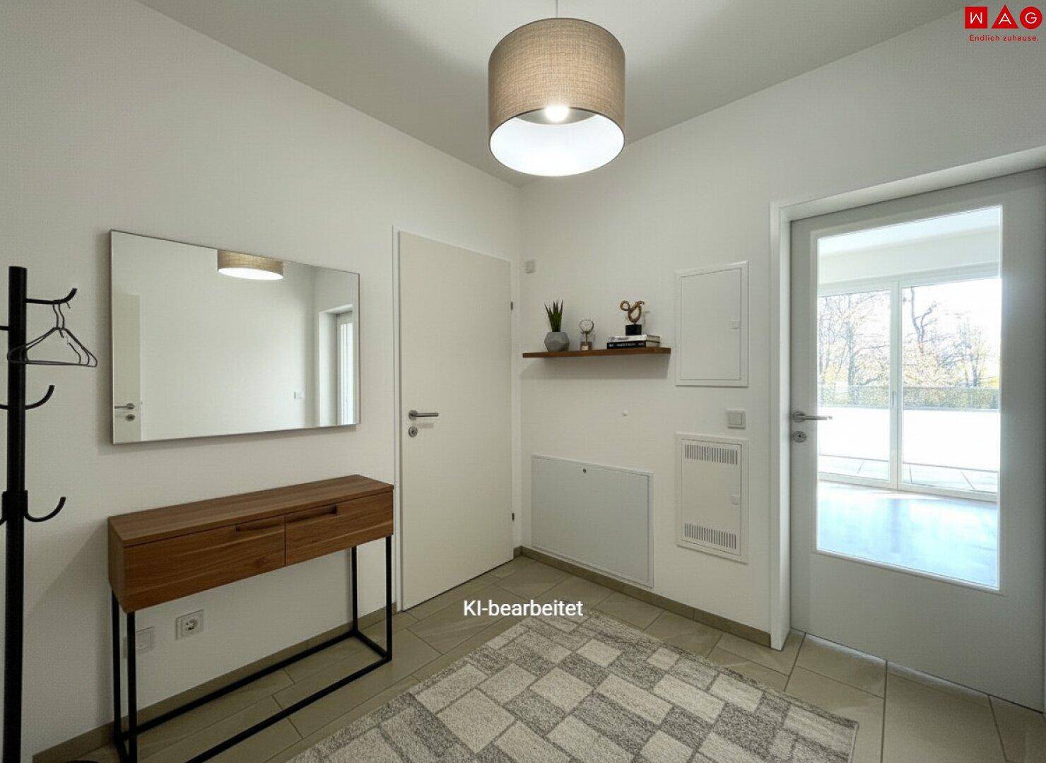 Heller Eingangsbereich mit Fliesenboden, Spiegel und Garderobe, der zum Wohnbereich führt.