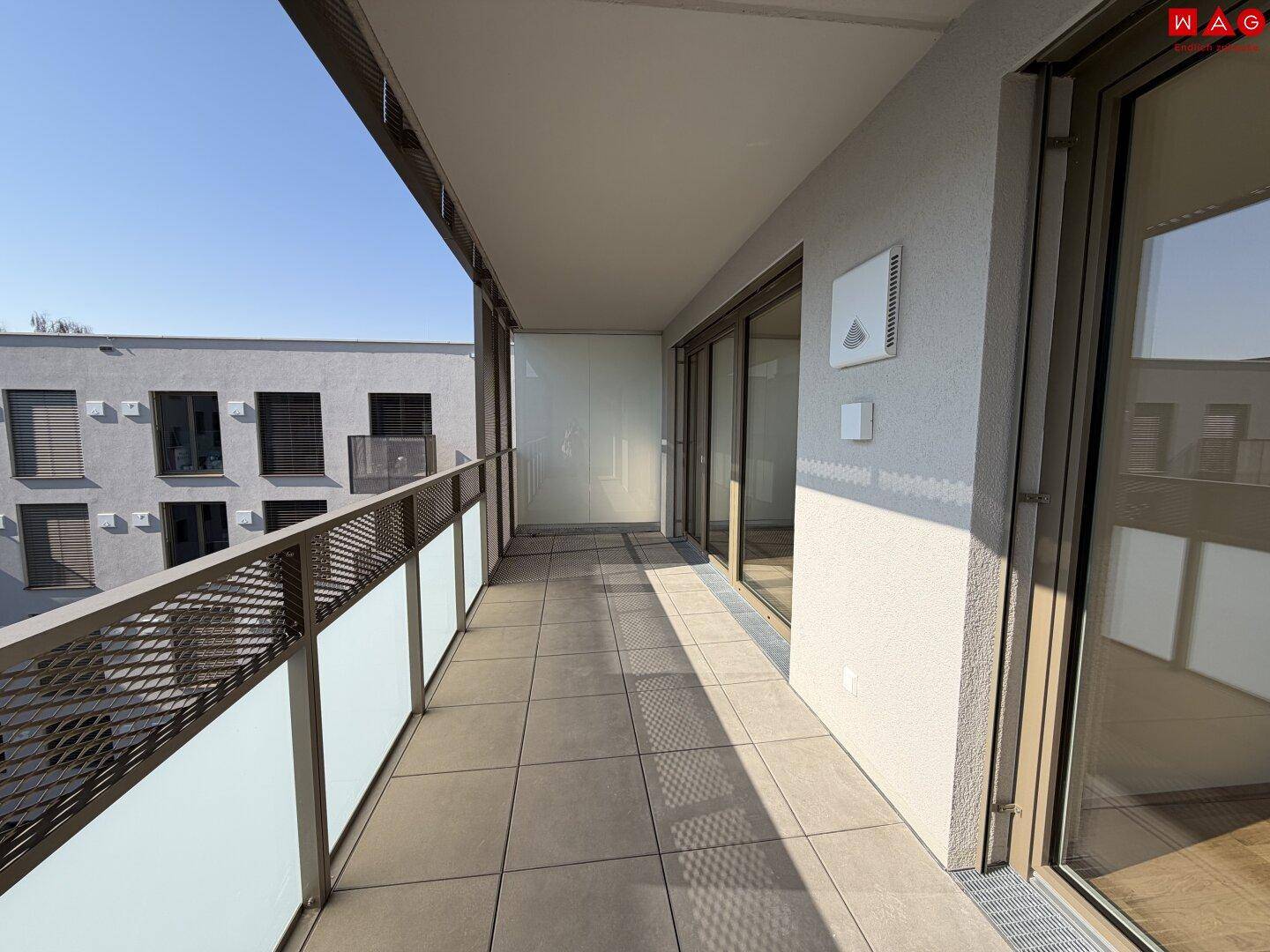 Geräumiger, leerer Balkon mit Fliesenboden und moderner Metallbrüstung.