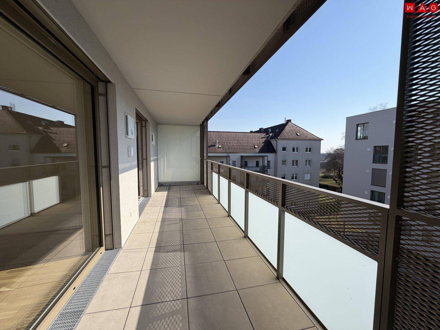 Langer Balkon mit Fliesenboden und Blick auf die umliegenden Gebäude.