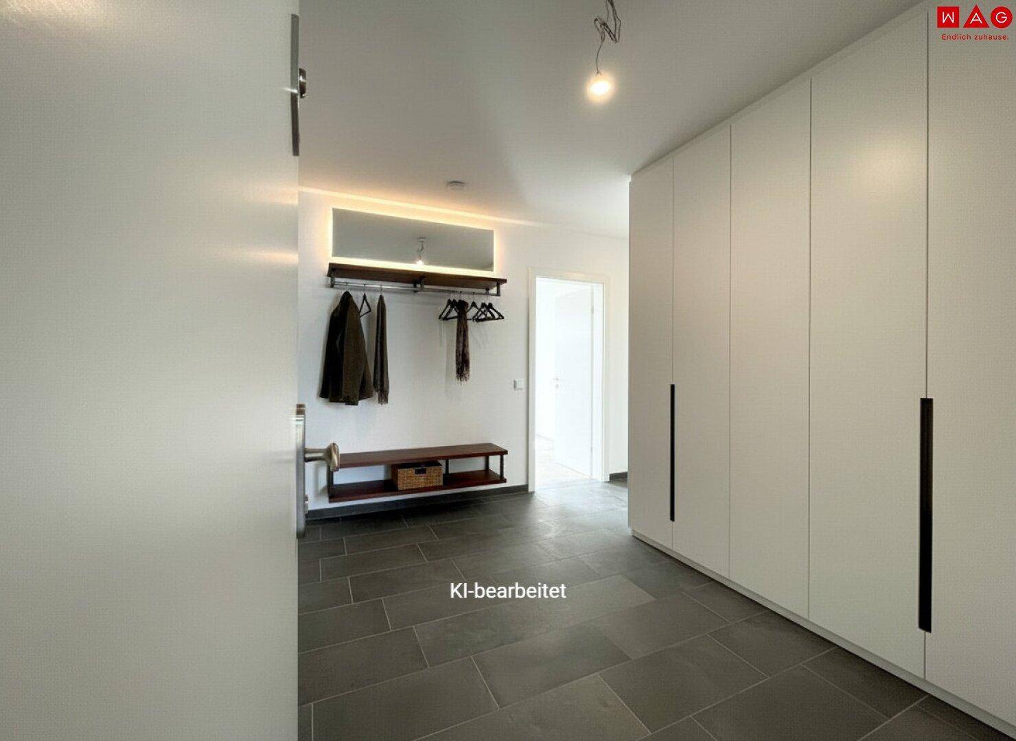 Heller Eingangsbereich mit modernen Einbauschränken, Garderobe und dunklem Fliesenboden.