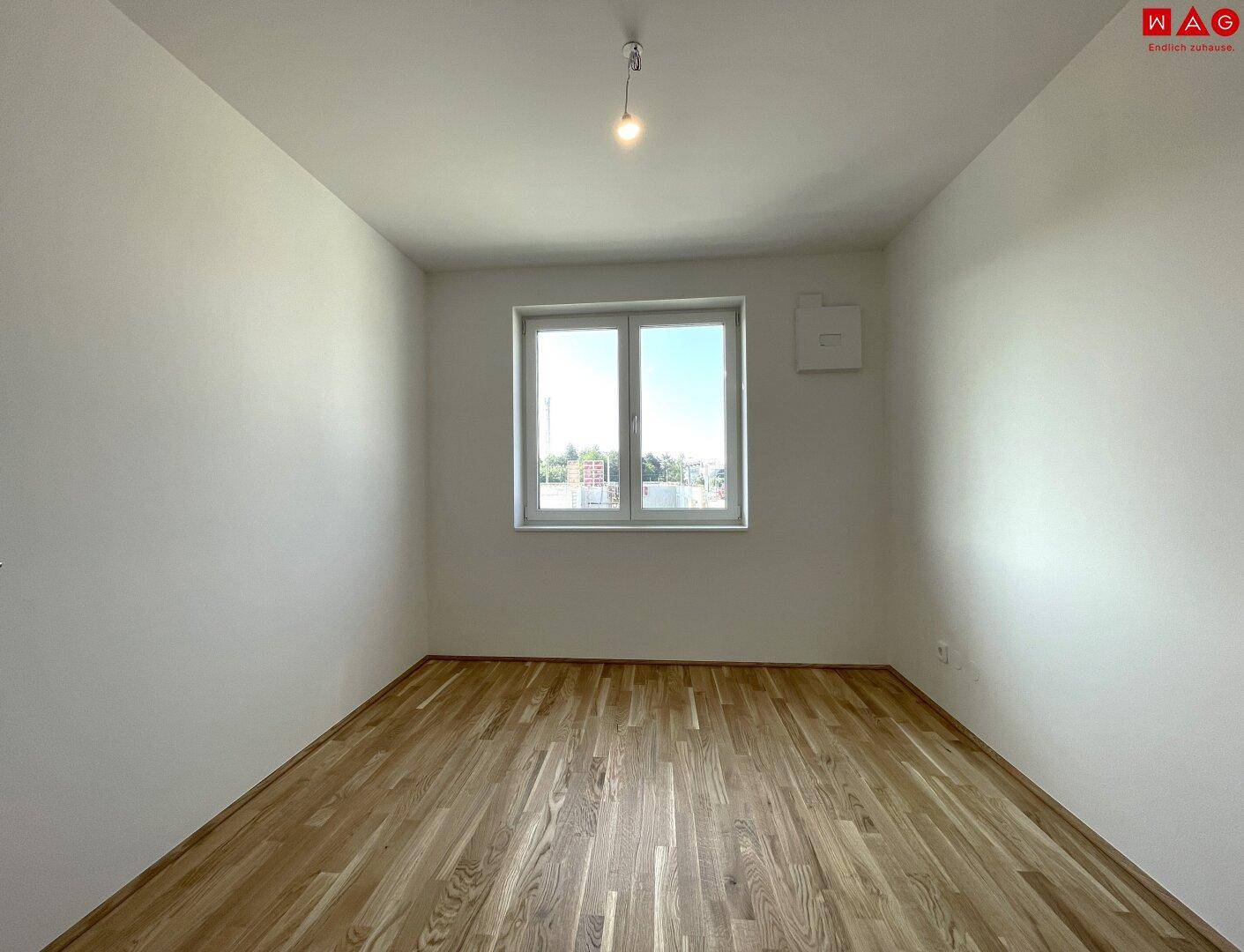 Unmöbliertes Schlafzimmer mit Holzboden und Fenster, bereit zur individuellen Gestaltung.