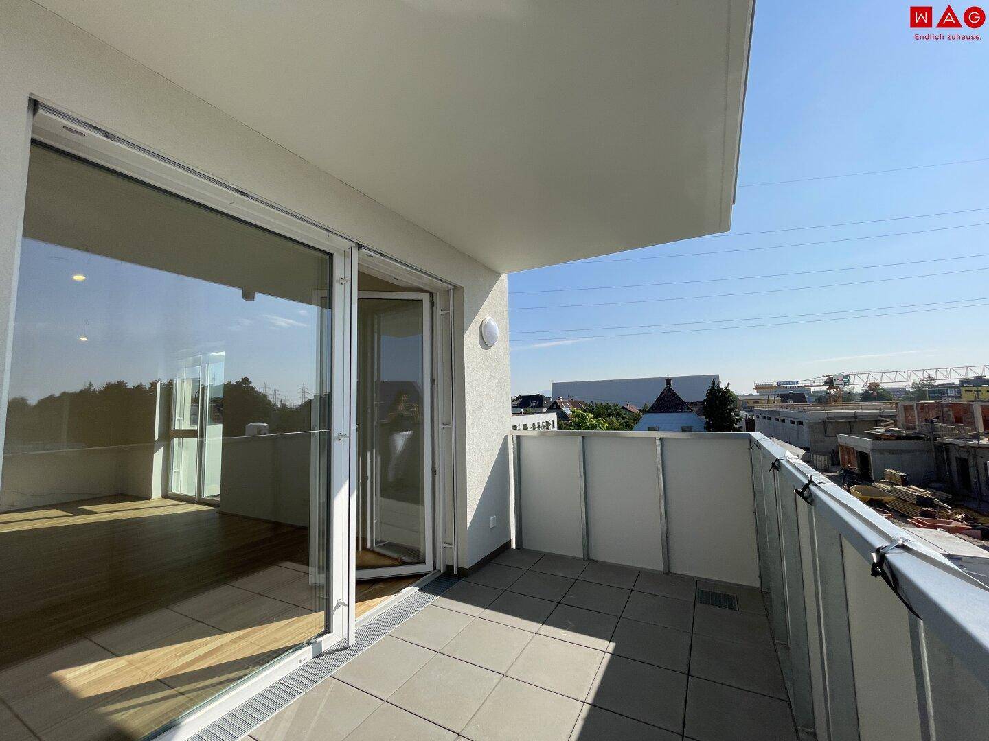 Geräumiger, leerer Balkon mit Fliesenboden und Blick auf die Umgebung.