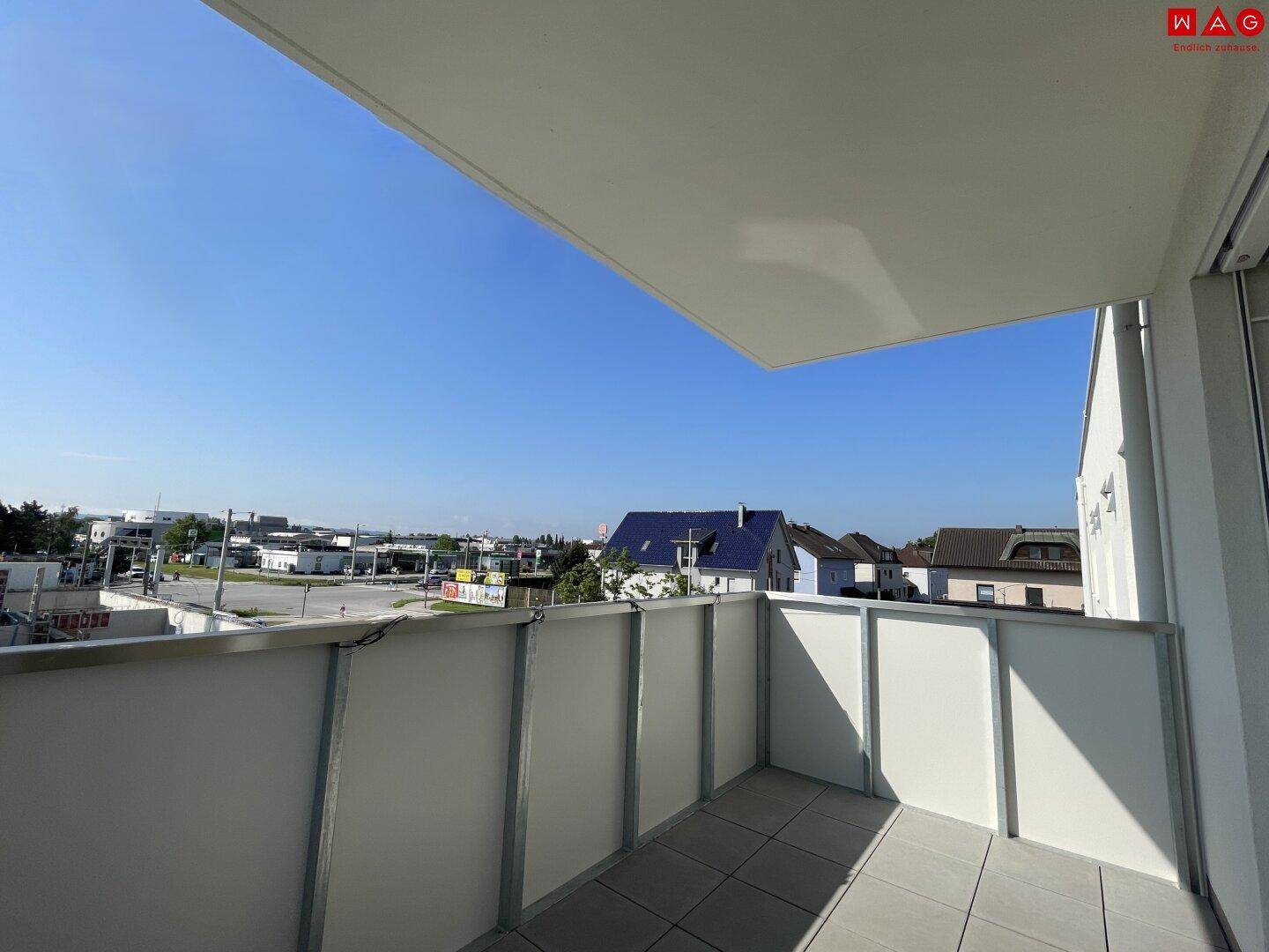 Heller, leerer Balkon mit Fliesenboden und weitem Blick über die Nachbarschaft.