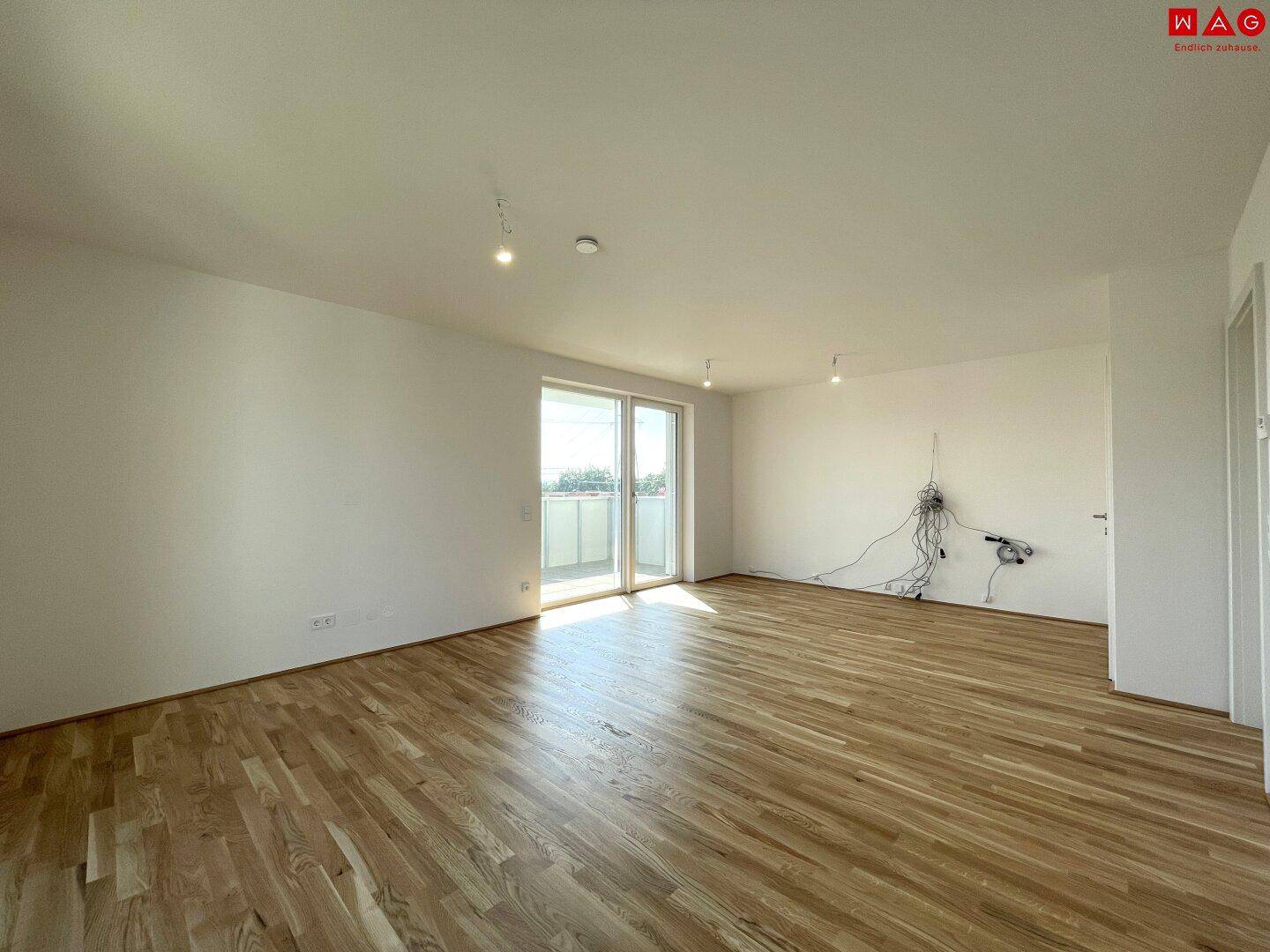 Helles Wohnzimmer mit Holzboden und Zugang zum Balkon, bereit zur individuellen Gestaltung.