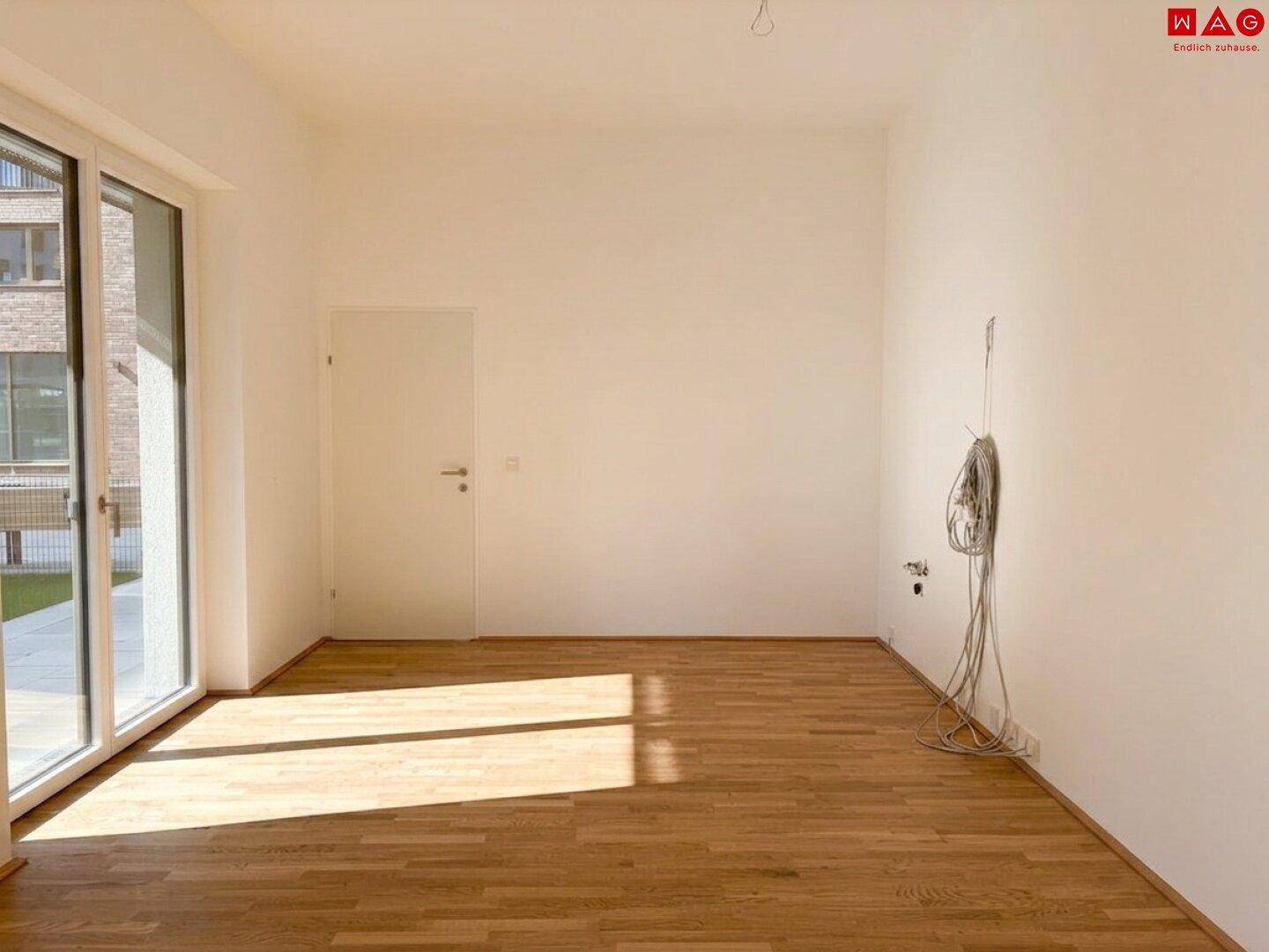 Lichtdurchfluteter Raum mit Holzboden und großen Fenstern, bereit für die Einrichtung.