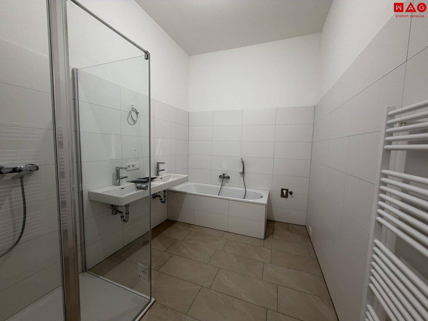 Modernes Badezimmer mit Dusche, Badewanne, Doppelwaschbecken und beheiztem Handtuchhalter.