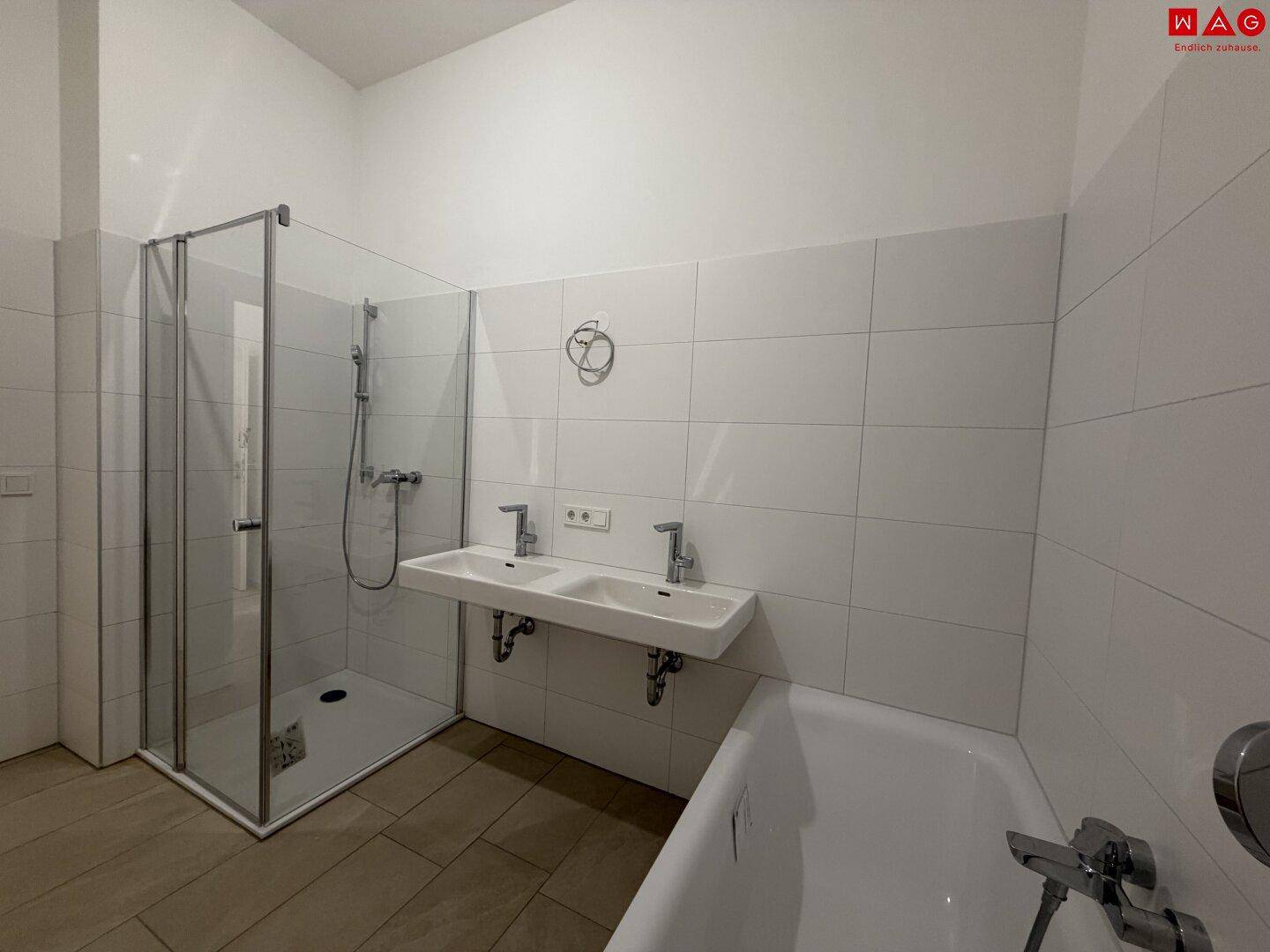 Helles Badezimmer mit Duschkabine, Badewanne und zwei Waschbecken in modernem Design.
