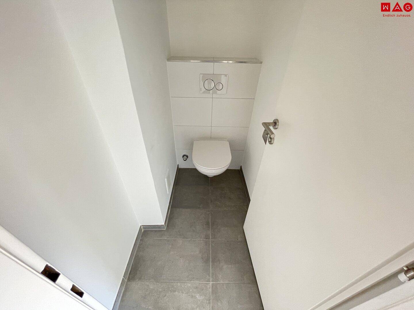 Kleines separates WC mit wandhängender Toilette und modernen Fliesen.