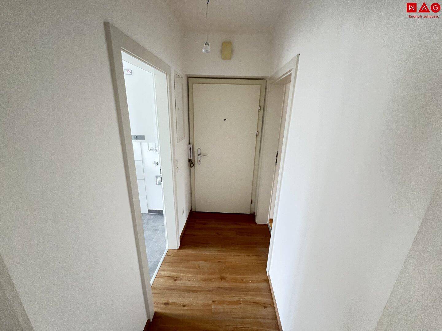 Heller Flur mit Laminatboden und Zugang zu verschiedenen Räumen.
