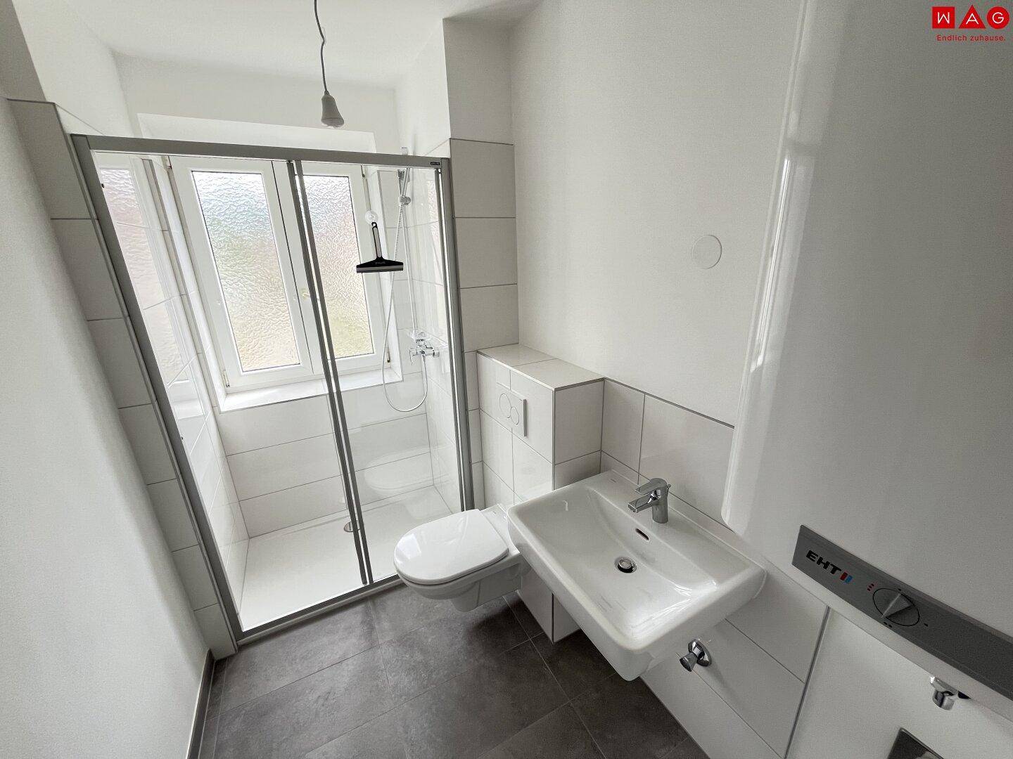 Modernes Badezimmer mit Dusche, Waschbecken und Fenster.
