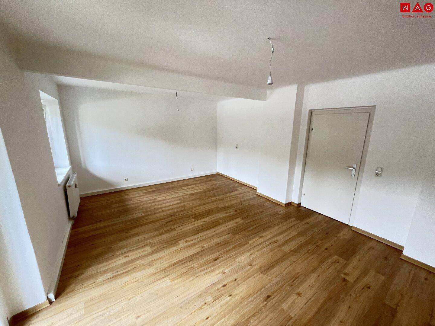 Geräumiges, helles Zimmer mit Laminatboden und weiß gestrichenen Wänden.