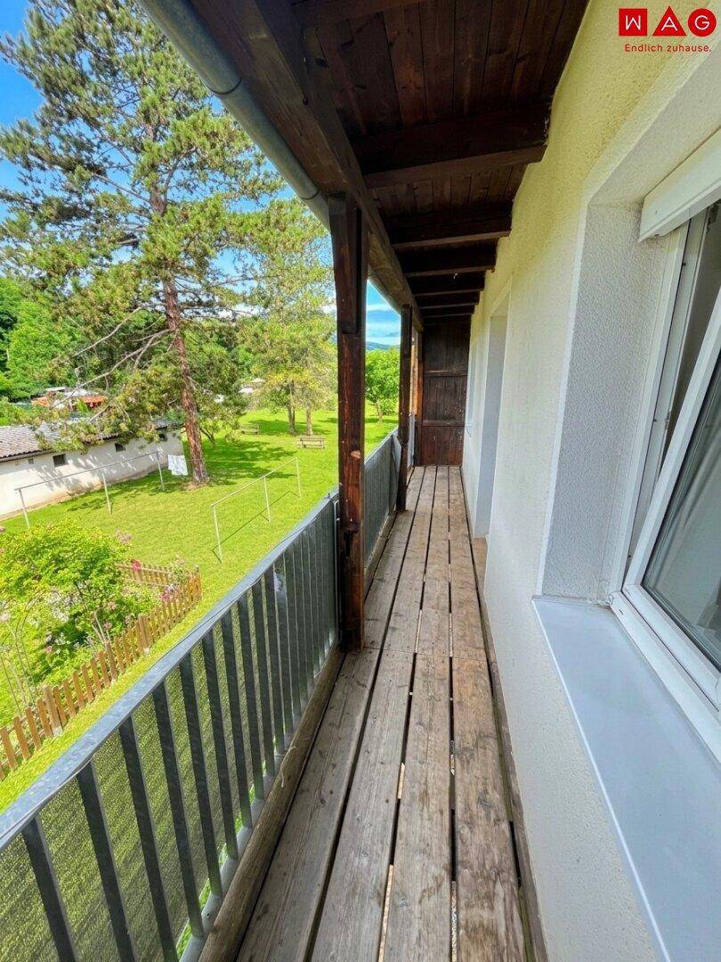 Langer Holzbalkon mit Metallgeländer und Blick ins Grüne.