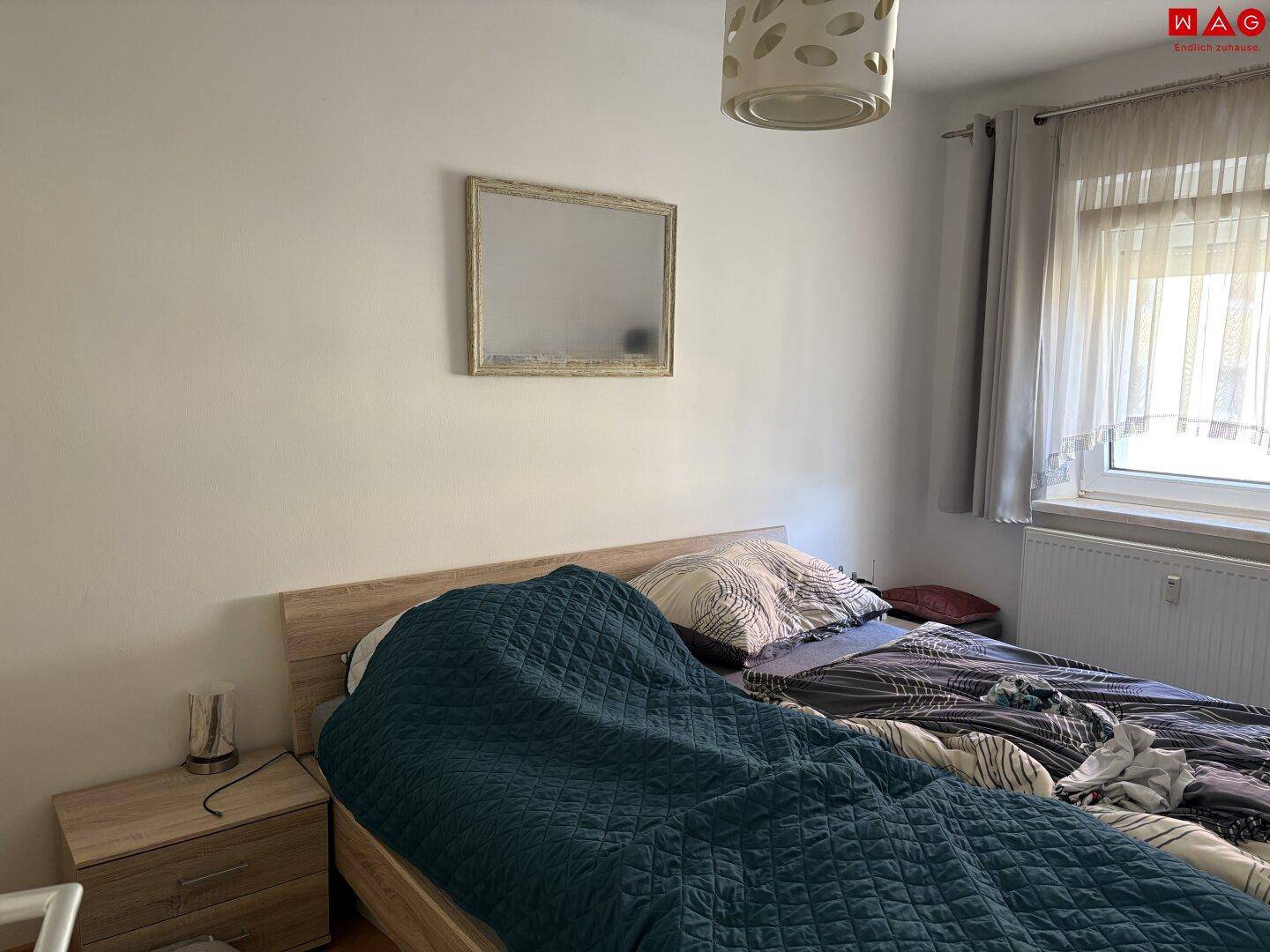 Schlafzimmer mit Doppelbett, Nachttischen und Fenster für natürliches Licht.
