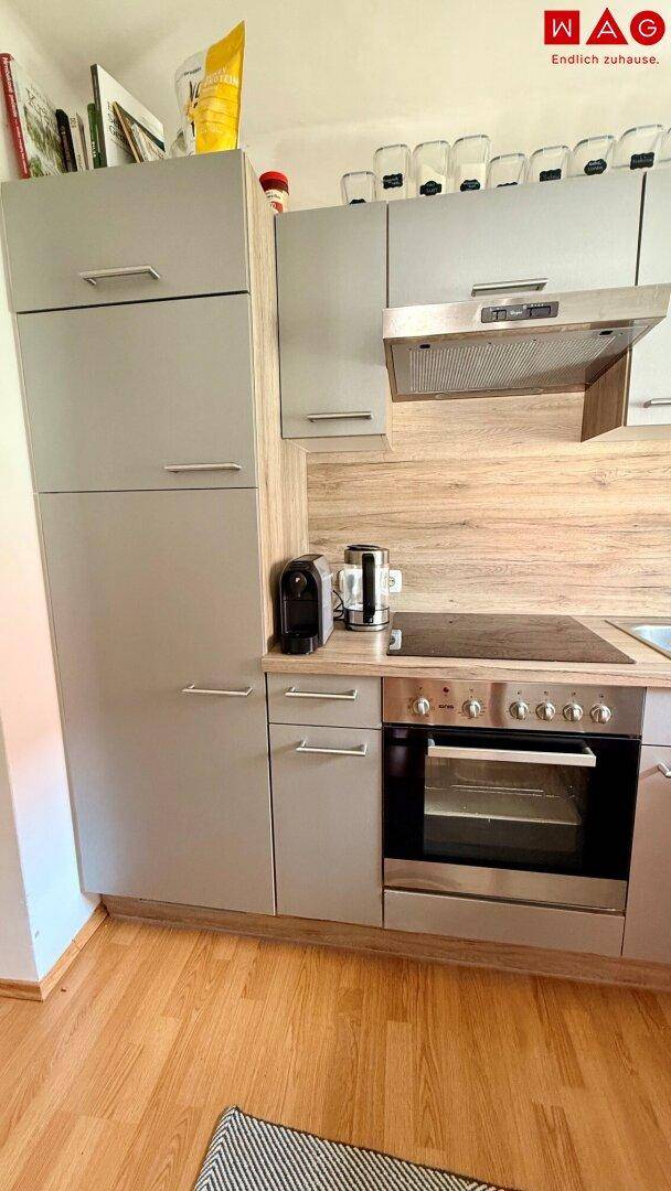 Detailansicht der modernen Küche mit hohen grauen Schränken, integriertem Backofen und Dunstabzugshaube.