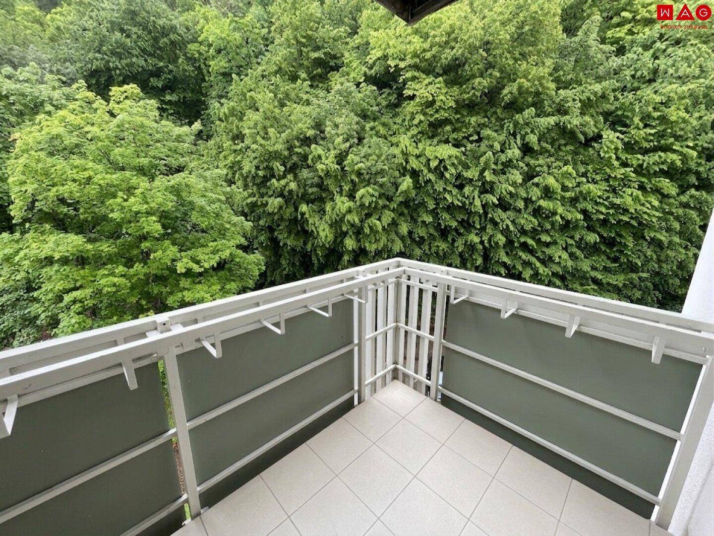 Heller Balkon mit Fliesenboden und einem schönen Ausblick ins Grüne, ideal zum Entspannen.