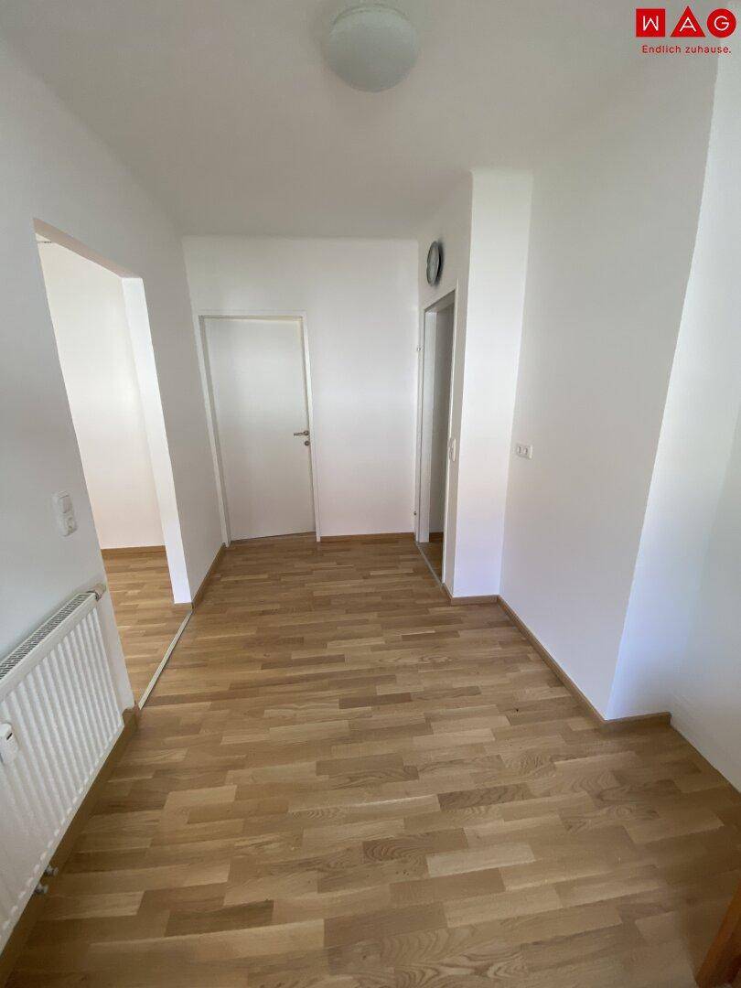 Geräumiger Flur mit Holzparkettboden und Heizkörper, der den Übergang zu den Zimmern bildet.