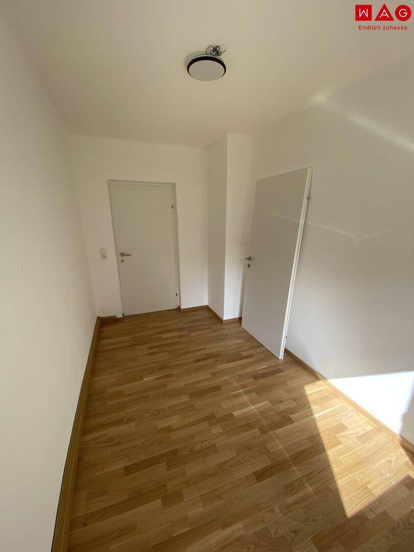 Heller Flur mit Holzparkettboden und zwei Türen, die zu verschiedenen Räumen führen.
