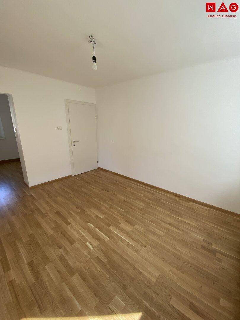Geräumiges Zimmer mit hellem Parkettboden und weißer Tür, bereit zur individuellen Gestaltung und Nutzung.
