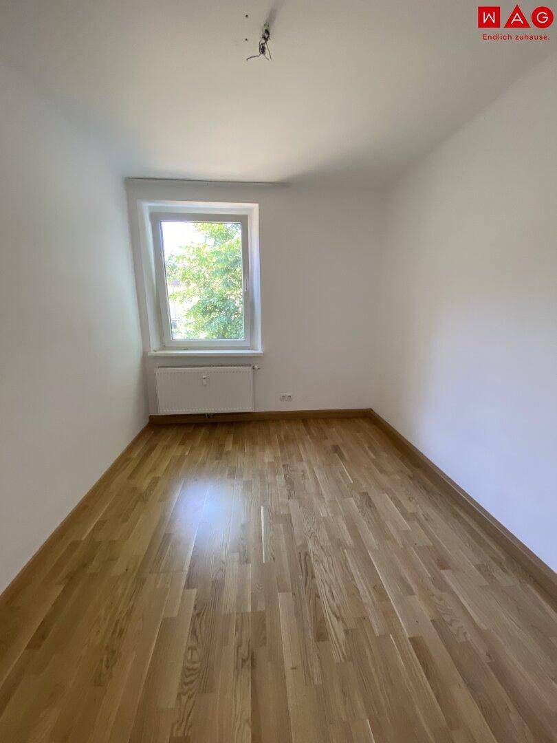 Gemütliches Zimmer mit Parkettboden und einem Fenster, das viel natürliches Licht spendet und Ruhe ausstrahlt.