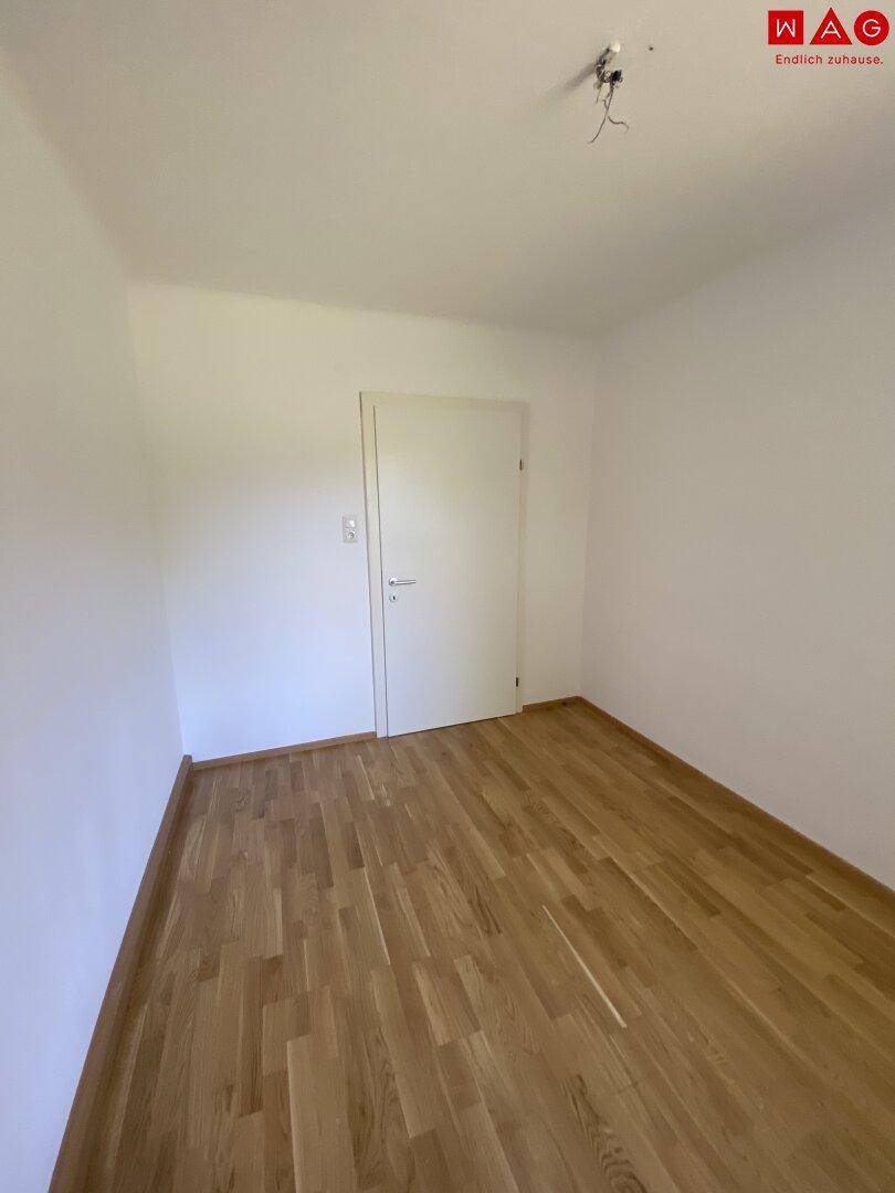Kleineres Zimmer mit Parkettboden und weißer Tür, geeignet als Schlaf- oder Arbeitszimmer mit einfacher Ausstattung.