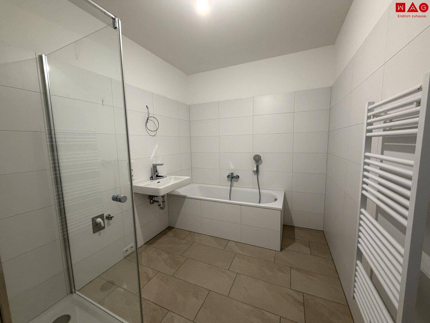 Unmöbliertes Badezimmer mit Badewanne, Duschkabine und weiß gefliesten Wänden.