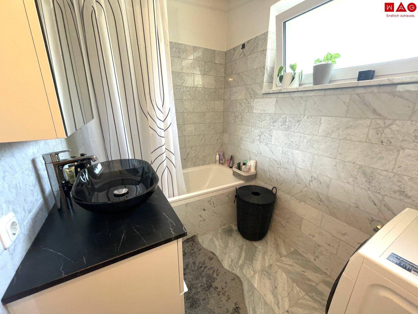 Modernes Badezimmer mit schwarzen Akzenten, Badewanne und Waschbecken.