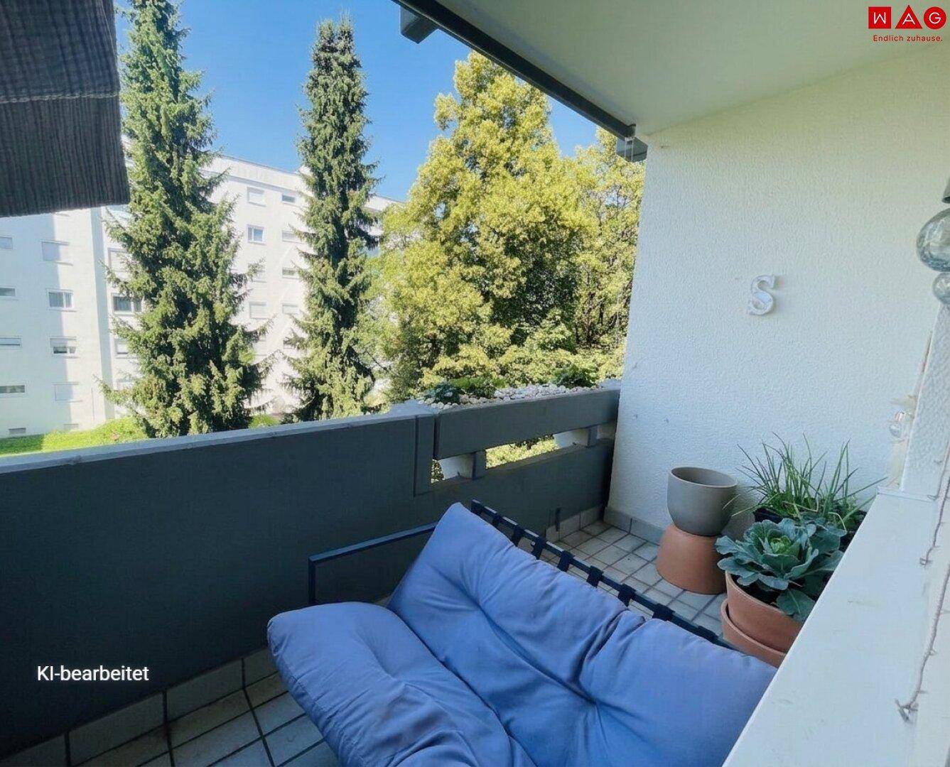 Gemütlicher Balkon mit Sitzgelegenheiten und Blick auf hohe Bäume und andere Gebäude.