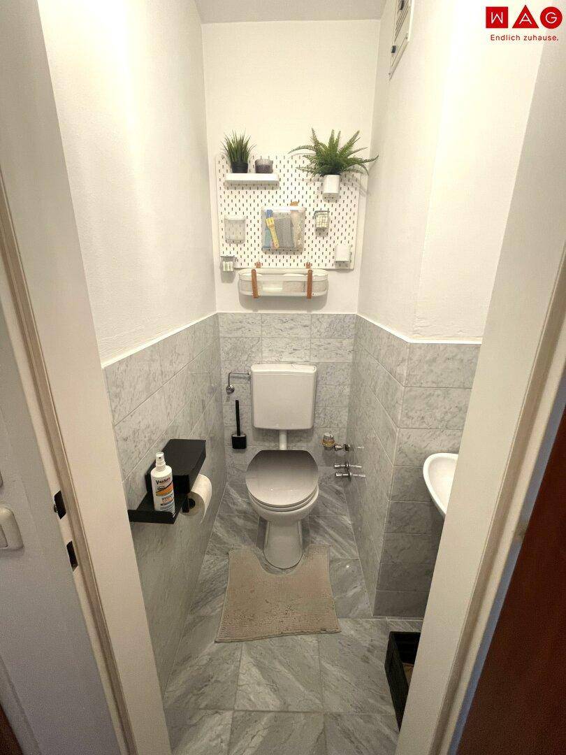 Kleines Gäste-WC mit modernen Fliesen, Wand-WC und kleinem Waschbecken.