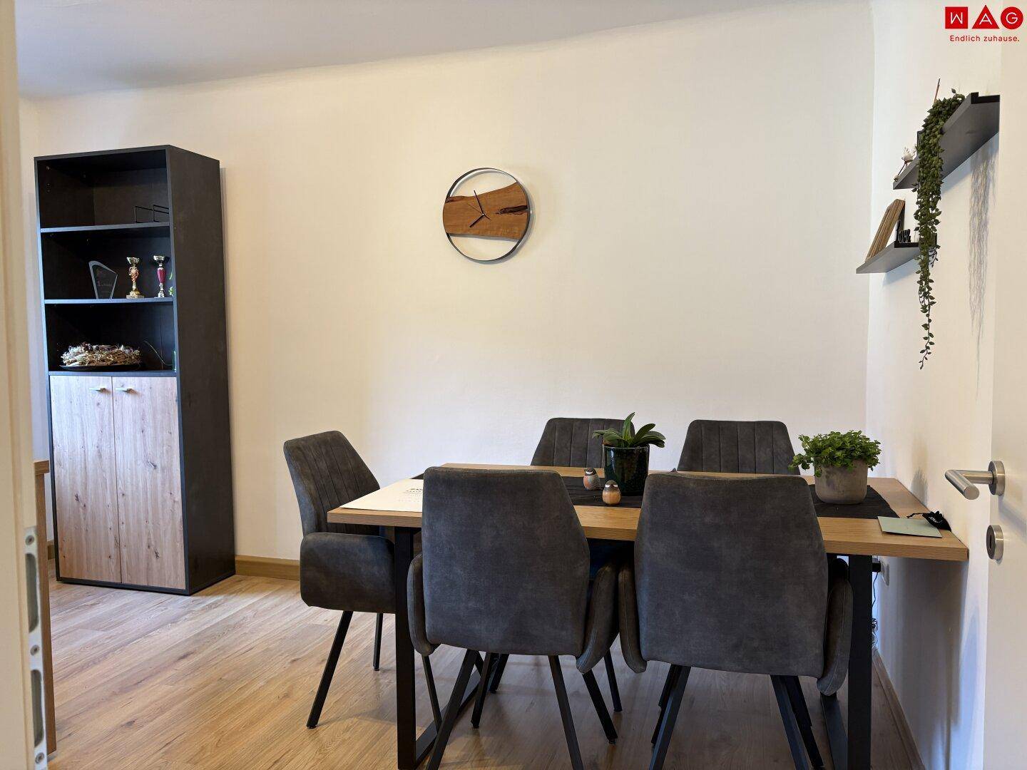 Heller Essbereich mit Holztisch, bequemen Stühlen und einem modernen Regal an der Wand.