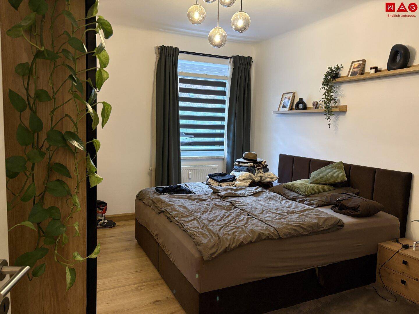 Schlafzimmer mit großem Doppelbett, Nachttischen und einem Fenster mit Blick nach draußen.