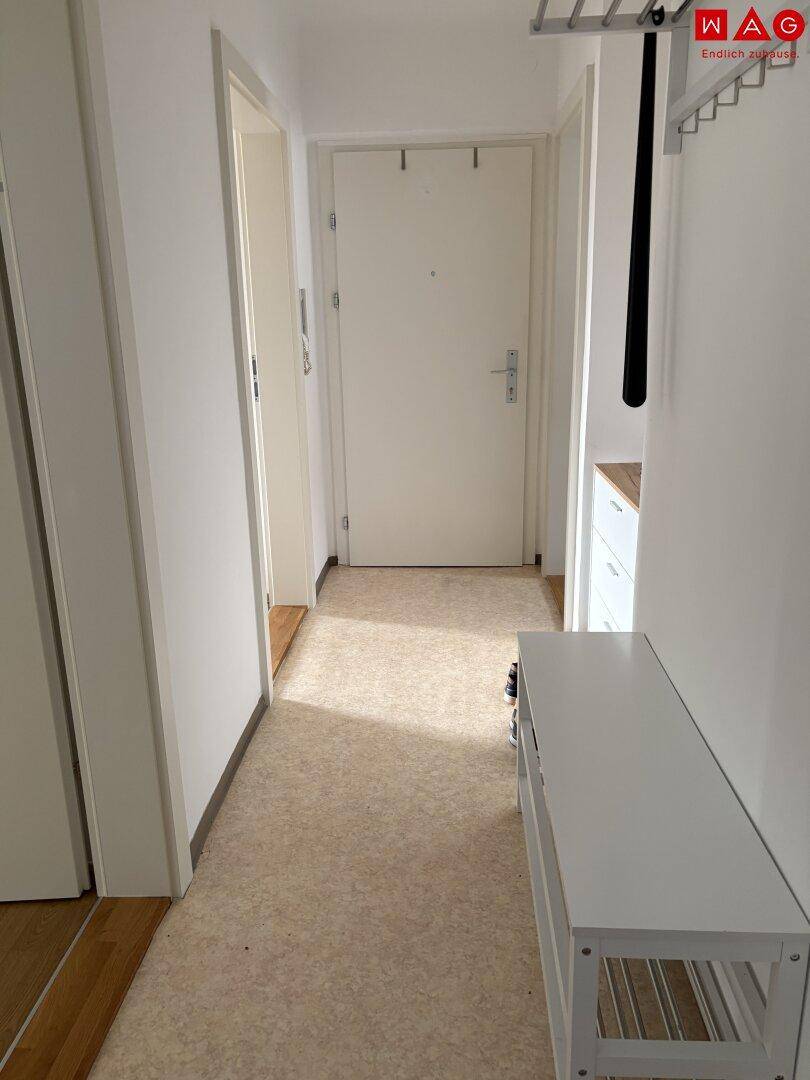 Heller Flur mit Garderobe, Sitzbank und Eingangstür, ausgestattet mit pflegeleichtem Boden.