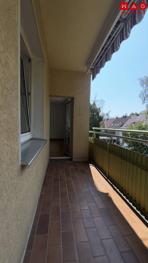 Geräumiger Balkon mit Fliesenboden und Zugang zu einem hellen Innenraum.