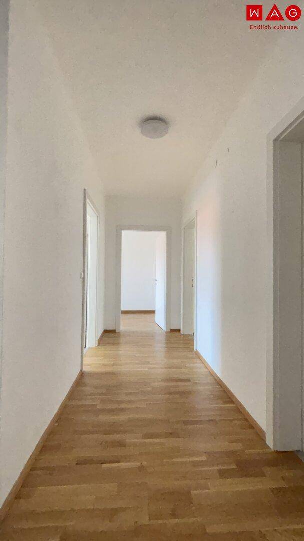 Heller Flur mit Parkettboden, der zu den verschiedenen Räumen der Wohnung führt.