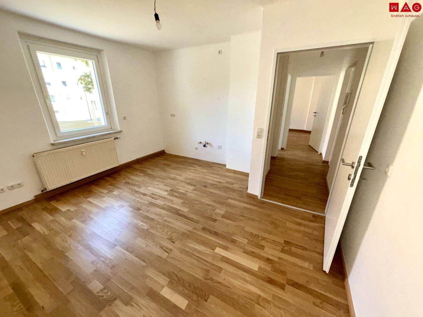 Geräumiges Zimmer mit Parkettboden und Zugang zum Flur, ideal als Schlaf- oder Wohnzimmer.