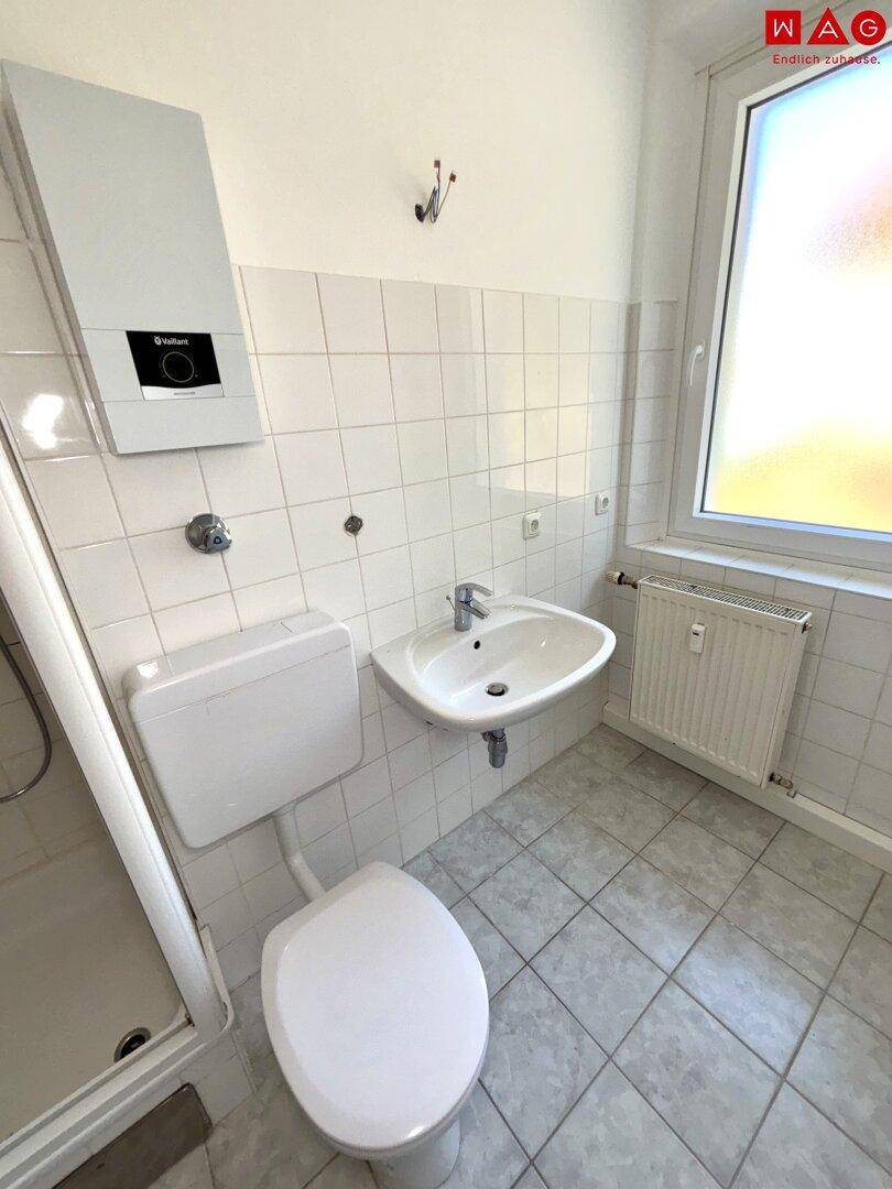 Funktionales Badezimmer mit WC, Waschbecken und Heizung, hell gefliest.