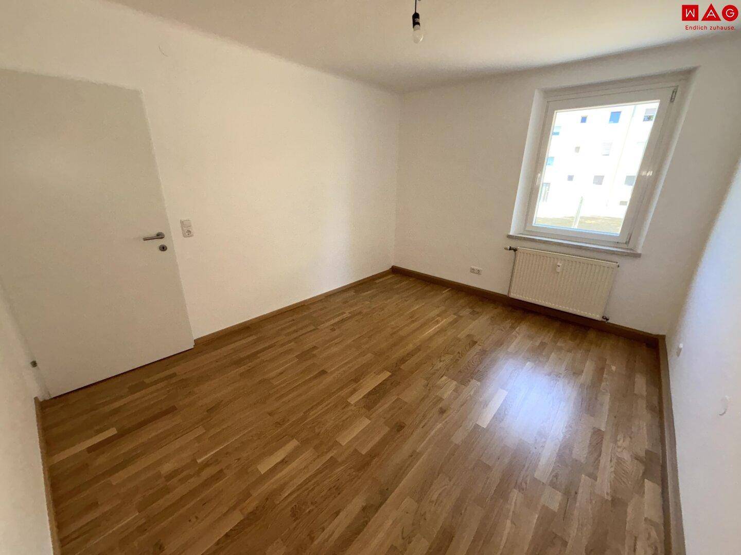 Geräumiges Zimmer mit Parkettboden und weiß gestrichenen Wänden, vielseitig nutzbar.